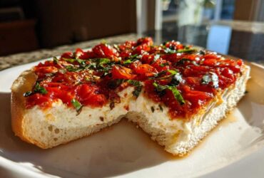 A thick slice of bread topped with creamy cheese and roasted tomatoes, representing the amazing bruschetta dip.