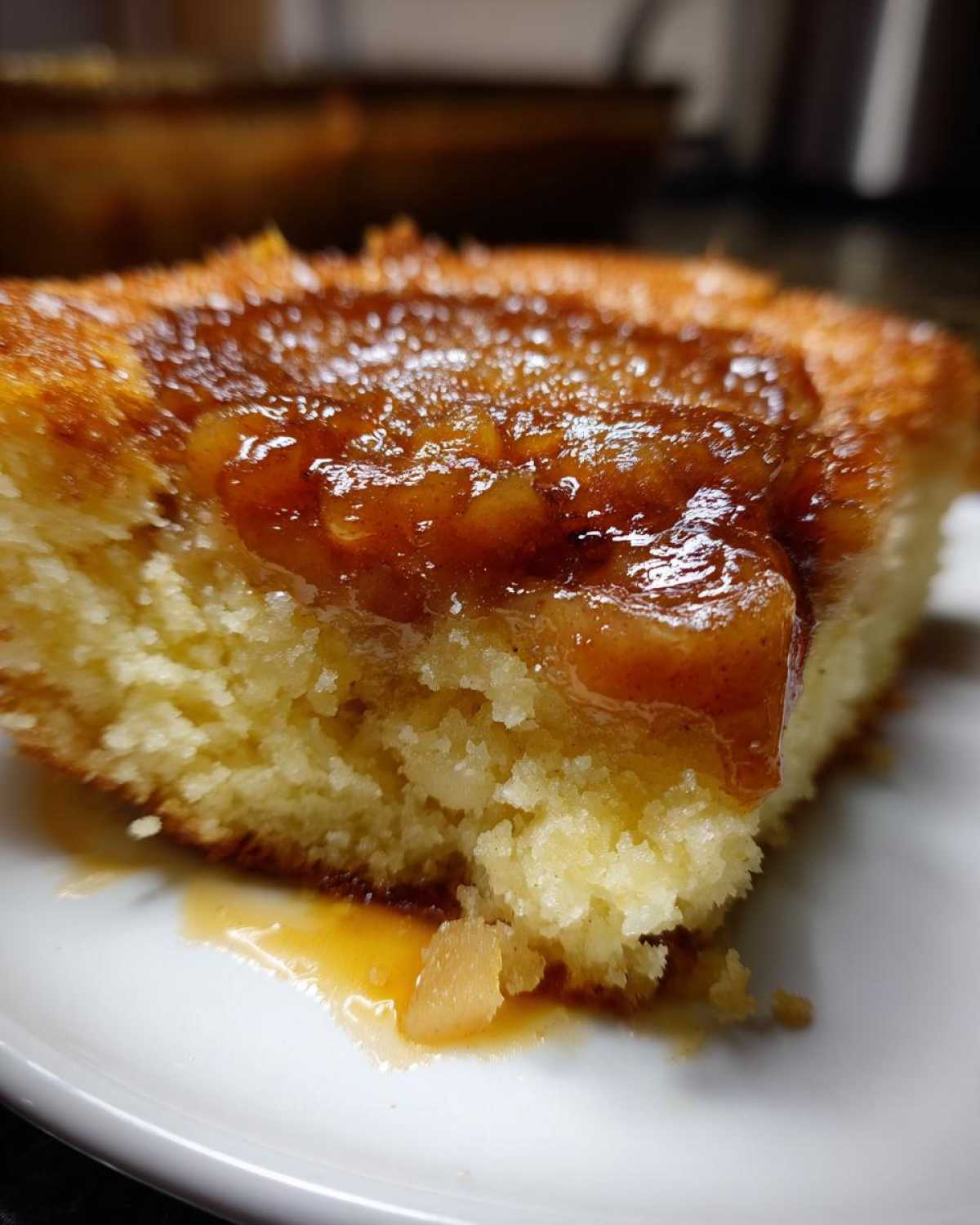 Close-up of a moist slice of caramel apple dump cake showing the fluffy cake base and gooey caramel apple topping.
