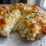 Three halves of a baked potato casserole, filled with mashed potatoes and topped with melted, browned cheese and fresh parsley.