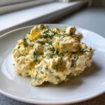 A mound of creamy egg salad mixed with visible chunks of egg and topped generously with fresh chopped dill.