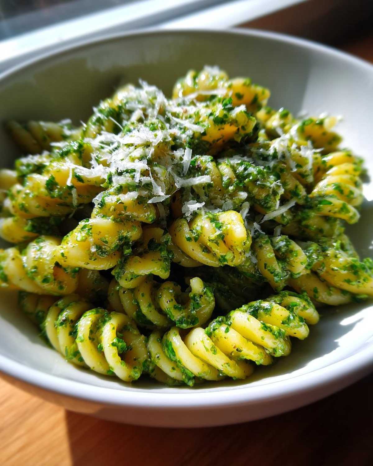 Close-up of creamy pesto pasta made with fusilli, topped with grated Parmesan cheese.