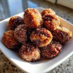 A pile of freshly made, glossy cinnamon sugar pecans coated heavily in sparkling sugar crystals.