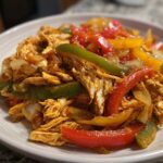 Close-up of shredded chicken mixed with colorful bell peppers and onions, ready for crockpot chicken fajitas.