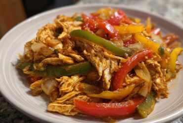 Close-up of shredded chicken mixed with colorful bell peppers and onions, ready for crockpot chicken fajitas.