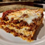 A thick, delicious slice of easy lasagna with ricotta, showing layers of pasta, meat sauce, and melted cheese.