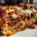 Close-up of a hearty slice of easy lasagna with ricotta, showing layers of pasta, rich meat sauce, and melted, browned cheese topping.