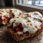 Close-up of two halves of an English muffin pizza topped with melted, slightly browned mozzarella cheese and tomato sauce.