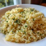 Close-up of fluffy mediterranean rice seasoned with lemon zest and fresh chopped parsley and dill in a white bowl.