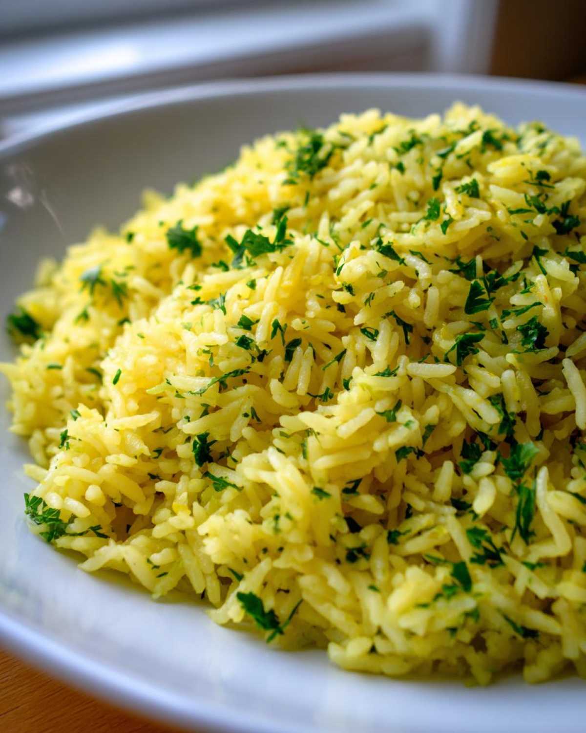 Close-up of bright yellow, fluffy mediterranean rice sprinkled generously with chopped green parsley.