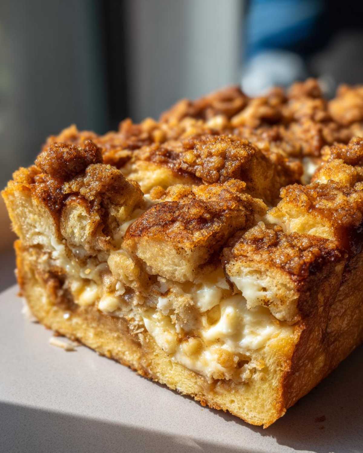 A close-up cross-section of a baked french toast casserole showing layers of soft bread, creamy filling, and a crunchy cinnamon streusel topping.