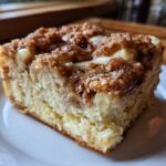 Close-up of a square slice of french toast casserole featuring a rich, gooey cream cheese filling and a crunchy cinnamon streusel topping.