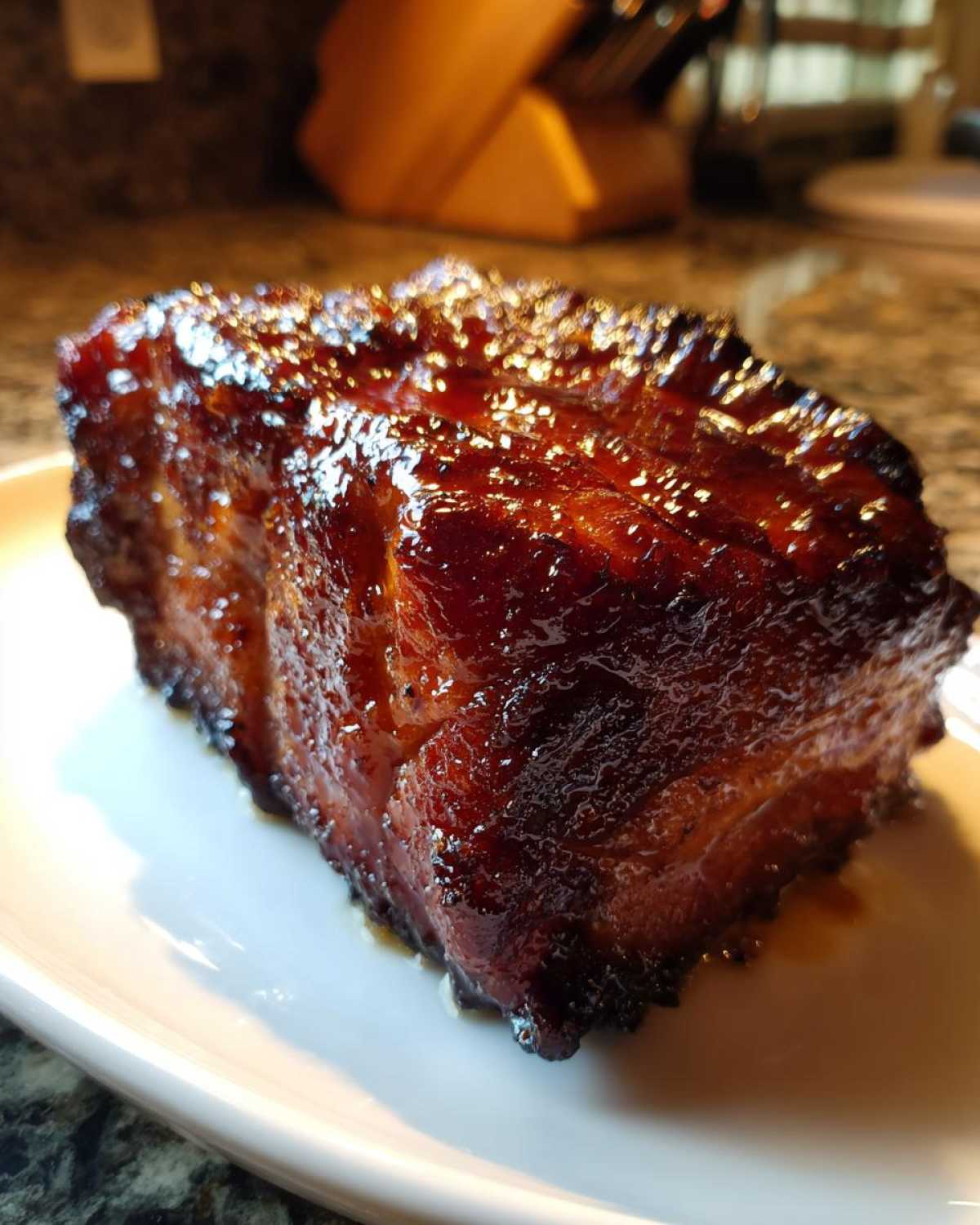 A thick, beautifully glazed piece of cooked pork steak resting on a white plate.