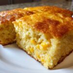 Close-up of a moist, golden slice of jiffy corn casserole showing whole corn kernels baked inside.
