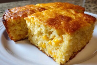 Close-up of a moist, golden slice of jiffy corn casserole showing whole corn kernels baked inside.