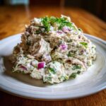 A generous scoop of creamy greek yogurt chicken salad mixed with red onion and herbs, topped with fresh dill.