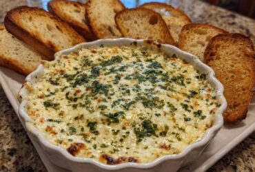 A bubbling, hot cheesy bread dip topped with parsley, served with toasted bread slices for dipping.