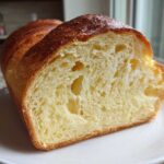 Close-up of a freshly baked japanese milk bread loaf, showing its soft, yellow, and airy interior crumb.