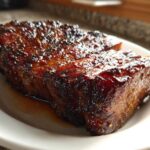 Close-up of a thick, juicy pork steak recipe cut, featuring a dark, caramelized, and glossy glaze.