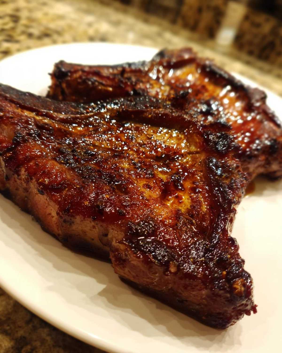 Close-up of two perfectly cooked, juicy pork steak cuts with a dark, caramelized glaze.