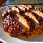 Close-up of sliced maple mustard pork tenderloin showing a caramelized, dark glaze and juicy interior.