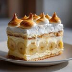 A decadent slice of old-fashioned banana pudding layered with vanilla wafers, sliced bananas, and topped with torched meringue peaks.