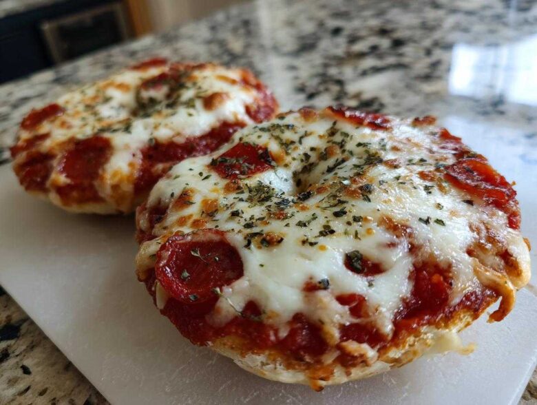 Two freshly baked pepperoni pizza bagels topped with melted mozzarella cheese and dried herbs, ready to eat.