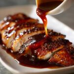 Thick, glossy homemade teriyaki sauce being poured from a white ladle onto sliced, seasoned chicken breast.