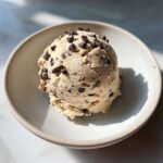 A perfect scoop of creamy high protein cookie dough studded with mini chocolate chips, served in a light bowl.