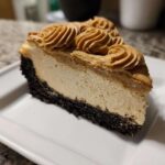A rich slice of biscoff cheesecake featuring a dark crust, creamy filling, and piped biscoff topping.