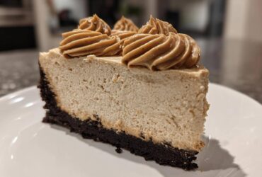 A close-up of a perfect slice of biscoff cheesecake featuring a dark crust and piped Biscoff topping.