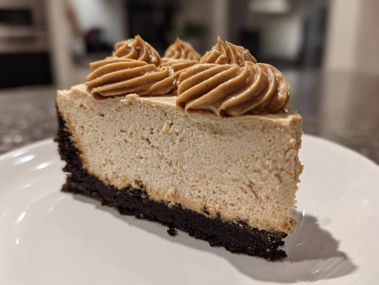 A close-up of a perfect slice of biscoff cheesecake featuring a dark crust and piped Biscoff topping.