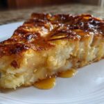 Close-up of a rich, gooey slice of caramel apple dump cake drizzled with caramel sauce.