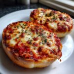 Close-up of two freshly baked pizza bagels topped with melted, bubbly cheese and sprinkled with parsley.