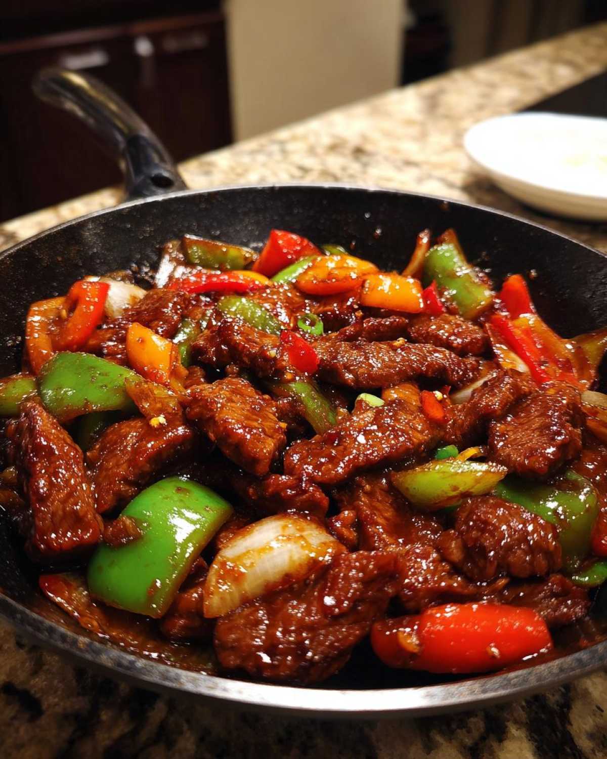 Close-up of tender pepper steak stir-fry with colorful bell peppers and onions coated in a rich sauce, ready to serve.
