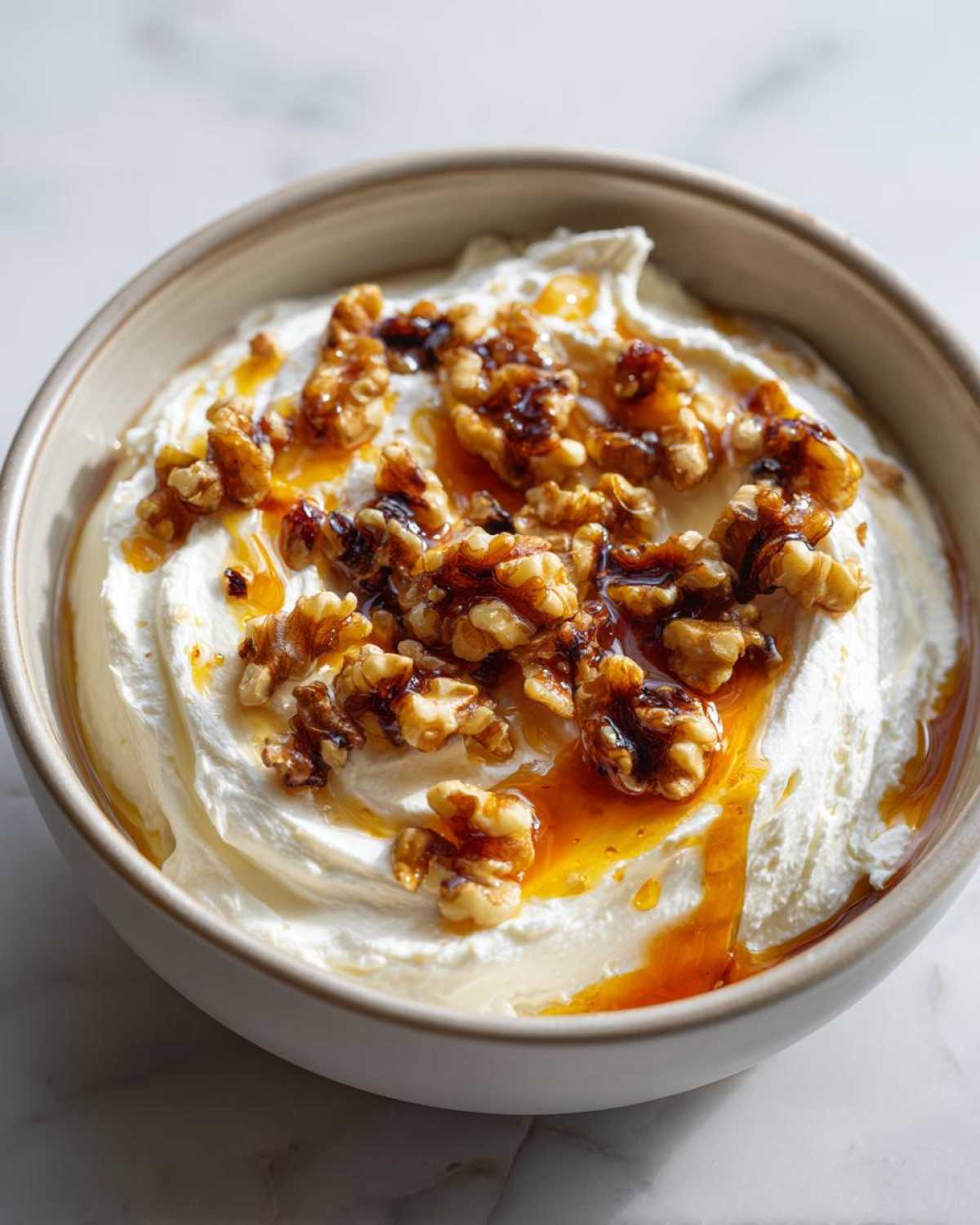 Close-up of a creamy whipped ricotta dip topped with caramelized walnuts and drizzled with honey.