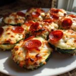 A white plate filled with freshly baked zucchini pizza bites topped with melted cheese and pepperoni slices.