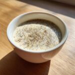 Close-up of creamy Chia Seed Pudding topped with extra seeds, sitting in a white bowl on a wooden surface.
