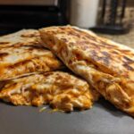 Close-up of golden brown Chicken Quesadillas cut into wedges, showing melted cheese and shredded chicken filling.