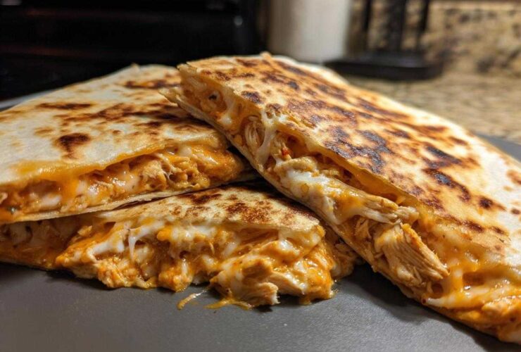 Close-up of golden brown Chicken Quesadillas cut into wedges, showing melted cheese and shredded chicken filling.