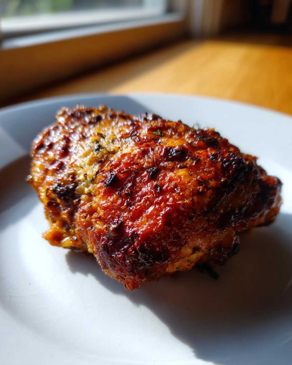Close-up of a perfectly cooked Air Fryer Garlic Parmesan Chicken Thigh with a crispy, browned exterior on a white plate.