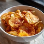 Close-up of crispy, golden Air Fryer Potato Chips seasoned with salt and spices in a white serving bowl.