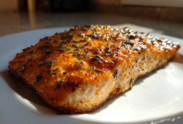 Close-up of a beautifully seasoned and cooked piece of Air Fryer Salmon on a white plate.