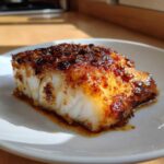 A close-up of a perfectly cooked piece of Baked Cod with Honey Garlic Sauce, featuring a caramelized, dark glaze.
