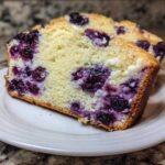 Two slices of moist Blueberry Cream Cheese Bread Loaf showing swirls of purple blueberries and white cream cheese filling.