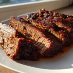 Four thick, juicy slices of slow-cooked brisket with a dark, caramelized exterior on a white plate.