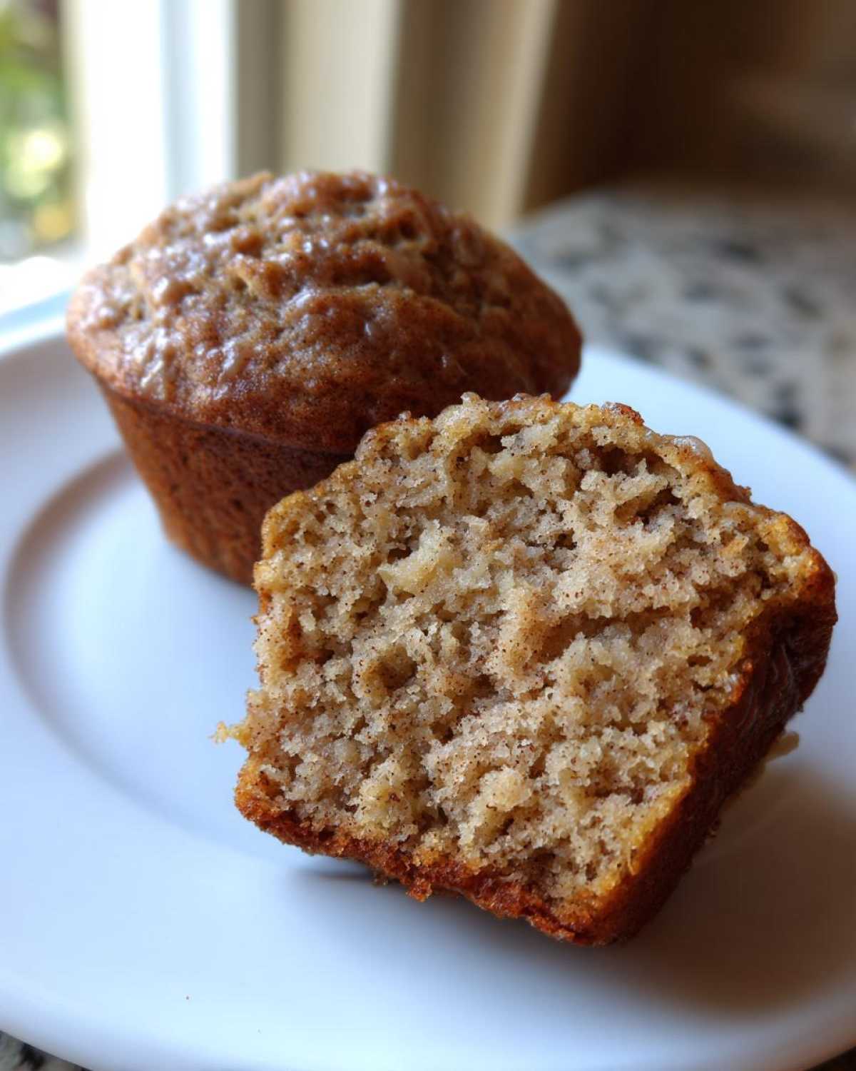 Close-up of a Brown Sugar Banana Muffin cut in half showing the moist, textured interior.