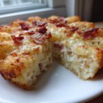 A close-up of a baked portion of Chicken Bacon Ranch Tater Tot Casserole, showing a crispy tater tot crust and creamy filling.