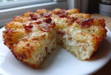 A close-up of a baked portion of Chicken Bacon Ranch Tater Tot Casserole, showing a crispy tater tot crust and creamy filling.