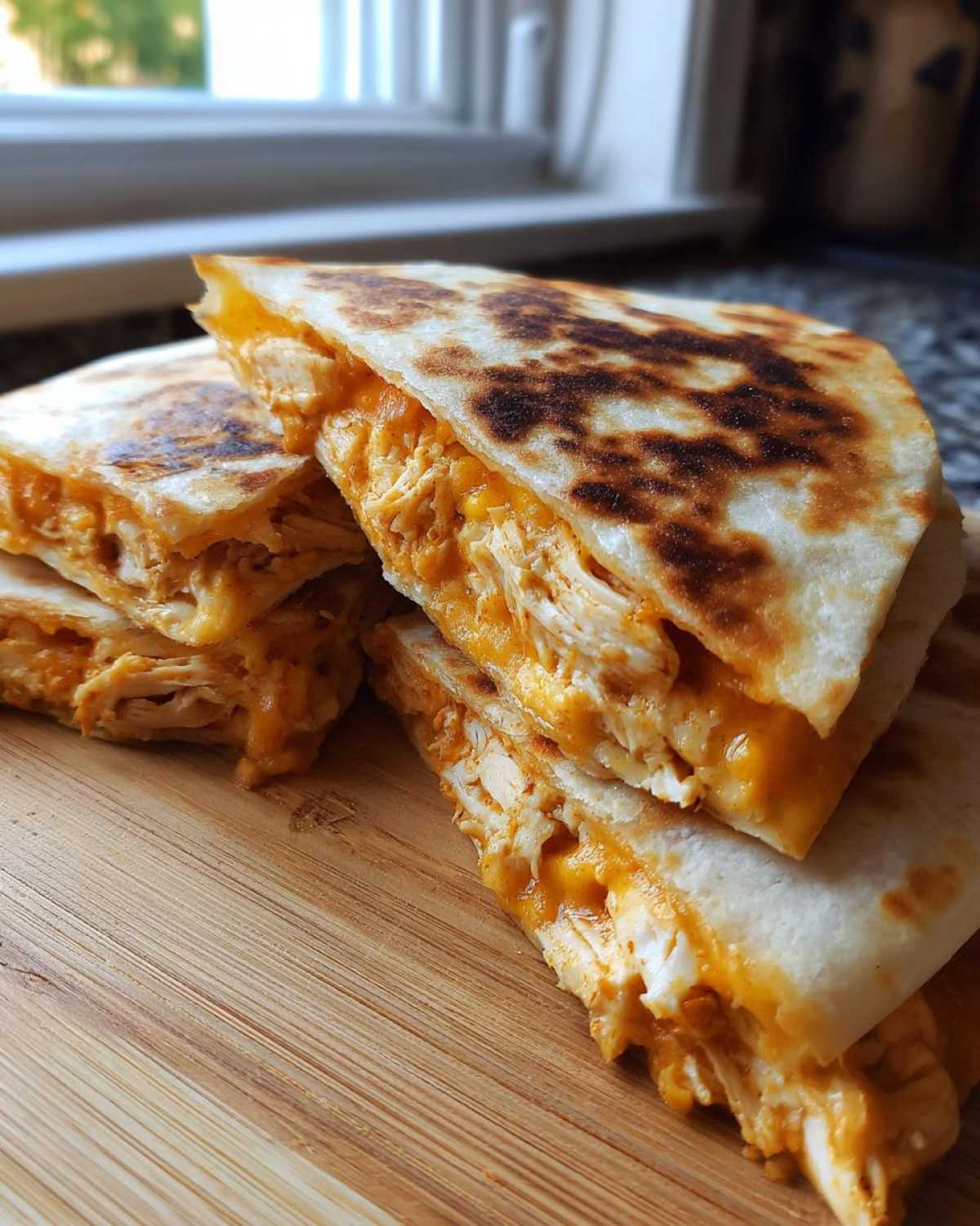 Close-up of stacked, golden-brown Chicken Quesadillas filled with shredded chicken and melted orange cheese.