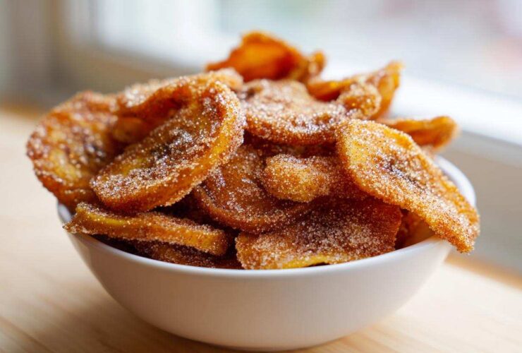 A white bowl filled with crispy Cinnamon Sugar Air Fryer Banana Chips, coated heavily in sparkling sugar.